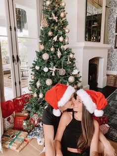 a man and woman sitting in front of a christmas tree