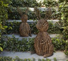 three straw sculptures sitting on top of steps in front of green bushes and ivys