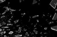 an abstract black and white photo with broken glass pieces flying in the air on a dark background