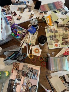 the table is cluttered with art supplies and paper on it, including pens, scissors, markers, pencils