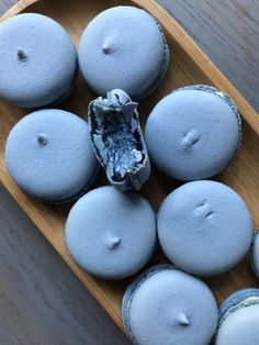 a wooden tray filled with blue and white macaroons on top of a table