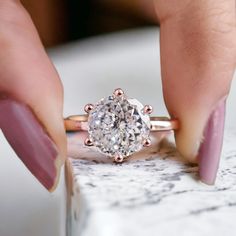 a woman's hand holding a ring with a diamond on it