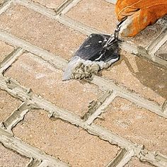 an orange glove laying on top of a brick floor next to a pair of scissors