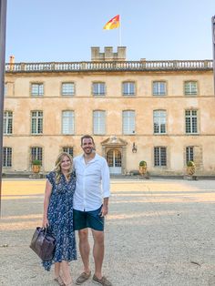 a man and woman standing in front of a large building with a flag on it