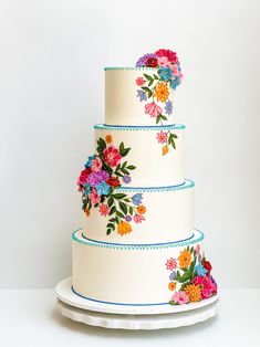 a three tiered cake with colorful flowers painted on it