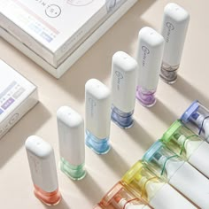 an assortment of different colored tubes on a table next to a book and other items