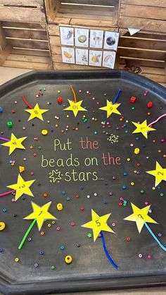 a black tray with yellow stars and writing on it that says put the beads on the 25 stars