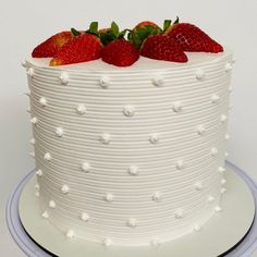 a white cake topped with strawberries on top of a blue and white platter