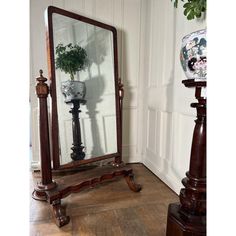 a large mirror sitting on top of a wooden stand next to a potted plant