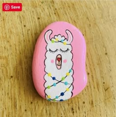 a painted rock with an image of a llama on it's face and beads around its neck