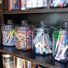 the shelves are filled with many different types of pens and pencils in glass jars