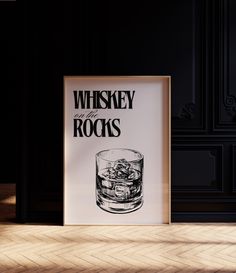 a poster with the words whiskey rocks on it in front of a black wall and wooden floor