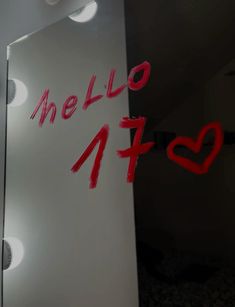 a mirror with the word hello written on it in red and black ink, next to a white wall