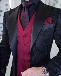 a man wearing a black and red tuxedo with his hands in his pockets