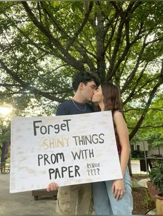 a couple kissing while holding a sign that says forget shiny things from with paper