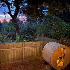 an outdoor sauna is lit up at night in the backyard with trees and bushes