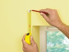 a man is measuring the wall with a tape measure