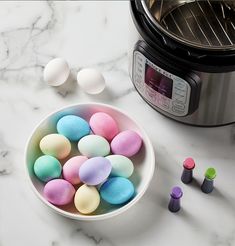 small plastic eggs in a bowl next to an electric pressure cooker on a marble countertop