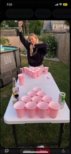 a woman standing in front of a table filled with pink cupcakes on top of it