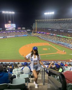 a woman sitting on the bleachers at a baseball game in front of an empty stadium