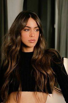 a woman with long brown hair wearing a black top