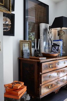 an old dresser with books and pictures on it