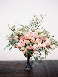 a vase filled with pink flowers on top of a wooden table