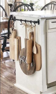 a kitchen island with cutting boards hanging from it's hooks and wooden utensils