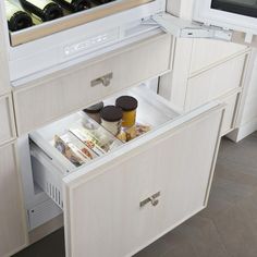 an open drawer in a kitchen with wine bottles and food items on the bottom shelf