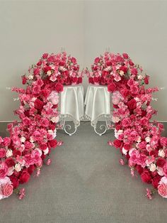 pink and white flowers are arranged in the shape of an arch on a gray carpet