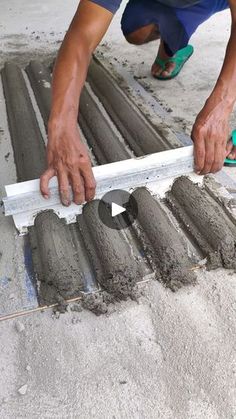 a man laying concrete on the ground with his hands and feet in front of him