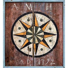 an old wooden door with a compass painted on the front and side panels that says amh