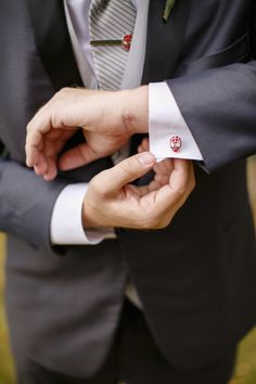 a man in a suit and tie adjusting his button on another mans lapel collar