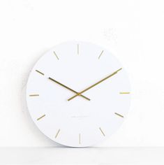 a white clock with gold hands on a wall