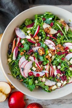 a white bowl filled with salad next to apples