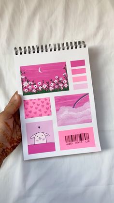 a hand holding up a notebook with pink and purple designs on it's cover