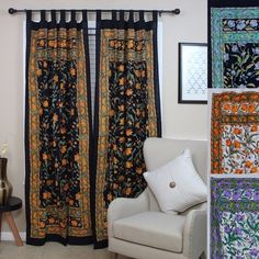 a white chair sitting in front of a window covered in black and orange floral curtains