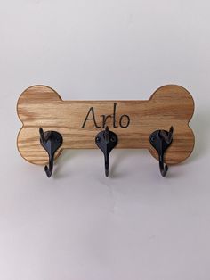 three coat hooks are attached to a wooden dog bone with the word arlo written on it