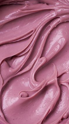 a close up view of pink frosting in a bowl with swirls on it