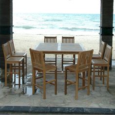 a wooden table and chairs sitting on top of a stone floor next to the ocean