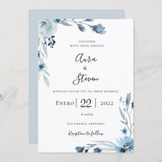 a wedding card with blue flowers and greenery on the front, in watercolor