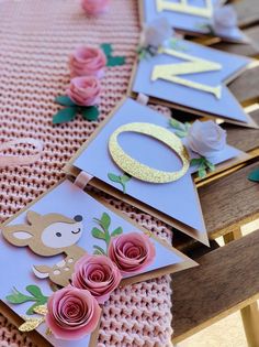 some cards are laying on a table with pink flowers and gold foil letters that spell out the letter n