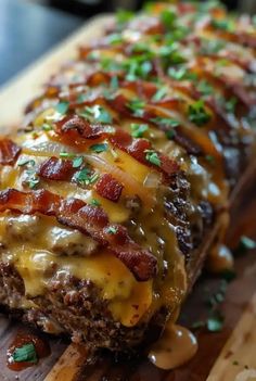 a meatloaf covered in cheese and bacon on a cutting board