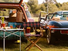 there are many cars that are parked in the grass and one has a table with food on it