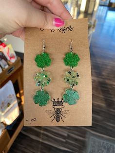 a pair of earrings with green beads and clovers hanging from it's ear wires