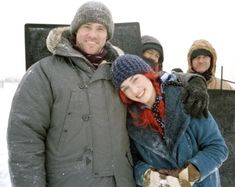 a group of people standing next to each other in the snow with one woman holding onto another man's arm