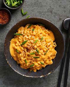 a bowl filled with macaroni and cheese on top of a table next to chopsticks