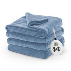 three blue towels stacked on top of each other with an electric thermometer next to them