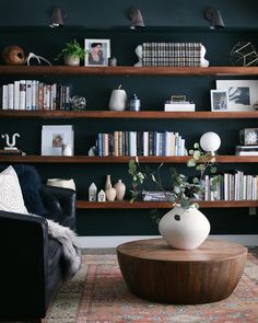 a living room filled with furniture and bookshelves next to a wall mounted book shelf