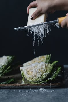 someone grating parmesan cheese on top of lettuce with a spatula